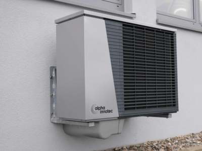 Heat pump unit mounted on exterior wall of residential building.